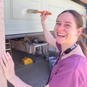 Smiling person paints the garage door