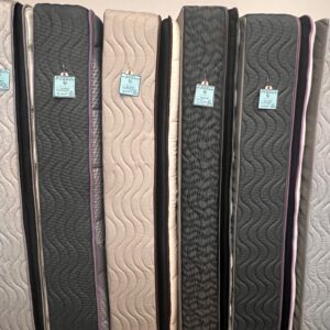 Several upright mattresses with different fabric patterns and blue price tags displayed in a store.