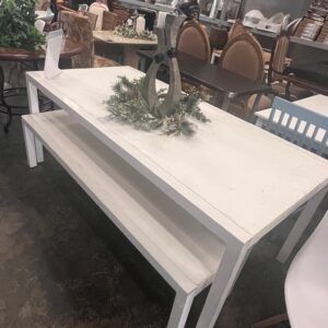 White console table with a holiday centerpiece on top, displayed in a secondhand furniture store.