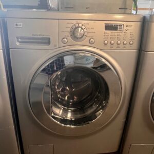 Front-loading silver LG washer and dryer combo with open detergent drawer, seen in a store.