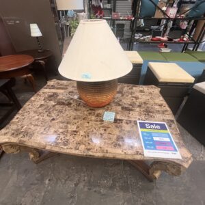 Marble coffee table with orange lamp and shade, on sale in a store with various furniture around it.
