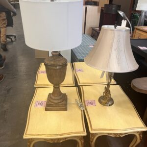 Two table lamps on yellow side tables in a furniture store, with more furniture in the background.