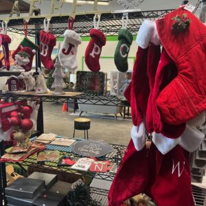 Christmas stockings, Santa hats, ornaments, and holiday decor displayed on black metal shelves in a store.