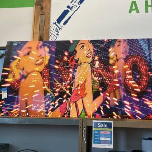 Colorful artwork of women and neon CASINO sign, with sale tags, displayed on a store shelf.