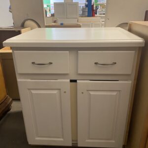 White kitchen cabinet with two drawers and two doors, displayed in a store with other cabinets around.