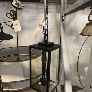 Black rectangular hanging lantern with a price tag, displayed in a store among other light fixtures.