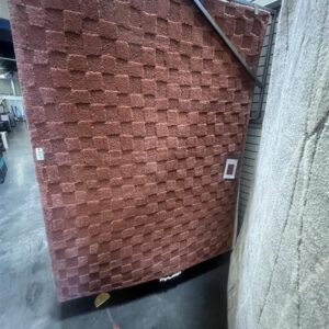 A large reddish-brown carpet with a raised checkerboard pattern displayed in a store.
