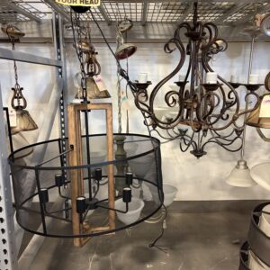 Various hanging light fixtures on display below a yellow Caution: Watch Your Head sign in a store.