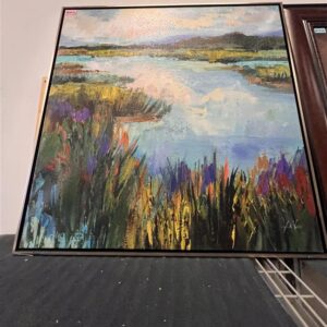 Framed painting of a colorful marsh landscape with water, grass, and sky, displayed on a dark surface.