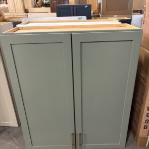 Green cabinet with two doors and silver handles, displayed in a warehouse or store setting.