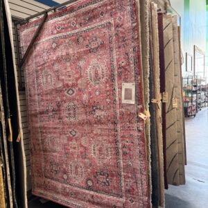 A display of hanging area rugs in a store, with a large red patterned rug in front.