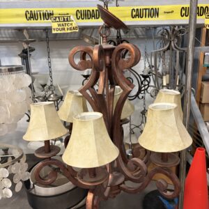 A brown chandelier with six cream lampshades hangs in a store with caution signs in the background.