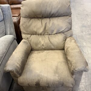 A brown, cushioned recliner chair with worn fabric, placed among other chairs in a showroom.