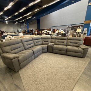 Large gray sectional sofa on a beige rug in a spacious furniture showroom with blue and gray walls.