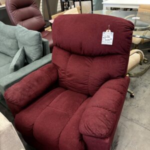 A plush red recliner with a price tag, displayed among other furniture in a store showroom.