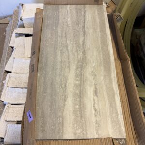 A rectangular gray and beige marble tile sits on an open cardboard box with price tags visible nearby.