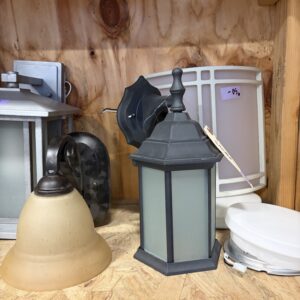 Assorted wall and ceiling light fixtures on a wooden shelf with a price tag on one lantern.