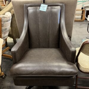 Dark brown leather office chair with high backrest, armrests, and wheels, surrounded by other furniture.