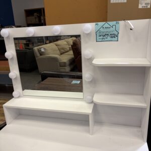 White vanity with large mirror, round lights, side shelves, and reflection of sofas and tables behind it.