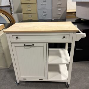 White rolling kitchen cart with shelves and a drawer, in front of several filing cabinets in a warehouse.