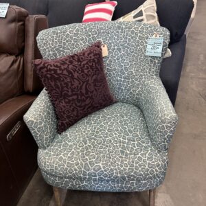 Blue-patterned accent chair with a purple decorative pillow, displayed in a furniture store.