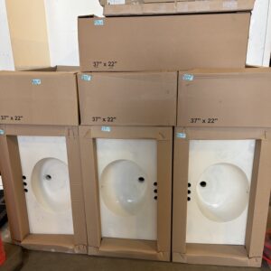 Three boxed white sinks, each labeled 37 x 22, stacked in front of more boxes against a wall.