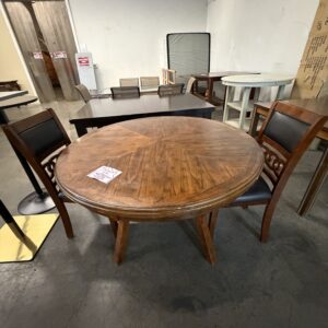 Round wooden table with two chairs in a room with various other tables and chairs in the background.