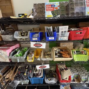 Store shelf with garden tools, seed starter kits, gloves, paintbrushes, bulbs, and various supplies.
