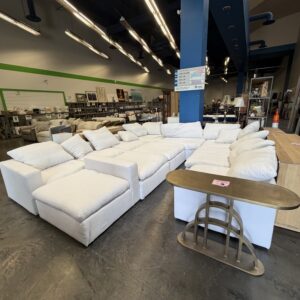 White sectional sofas are displayed inside a furniture store with modern lighting and decor.