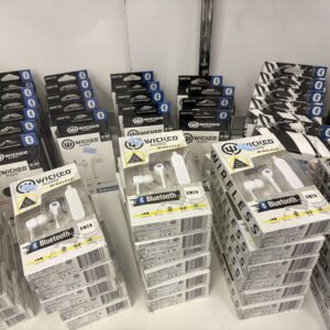 Stacks of boxed white Bluetooth earbuds on display, with other audio products in the background.