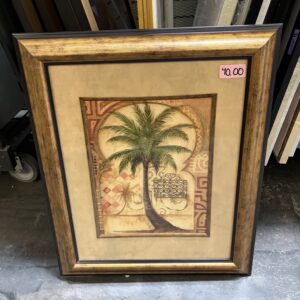Framed artwork of a palm tree with a $40 price sticker, placed on a concrete floor near other frames.