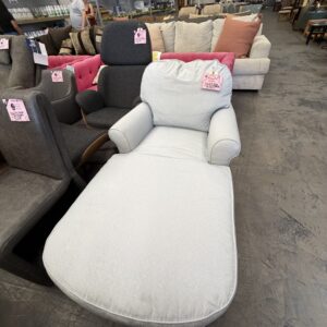 Light blue chaise lounge chair in a furniture store, surrounded by other chairs and sofas.