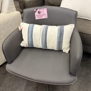 Gray armchair with a white cushion featuring blue stripes, displayed in a furniture store.