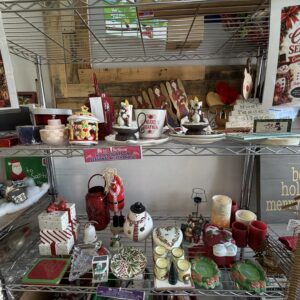 Shelves display assorted Christmas decorations, candles, mugs, and signs beneath Christmas in September posters.