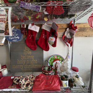 Christmas decorations and stockings hanging on a metal shelf with festive items and candles below.