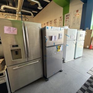 Several refrigerators of different styles are lined up on display in an appliance store showroom.
