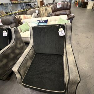 Gray and black armchair on display in a furniture store, surrounded by other sofas and chairs.