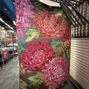 Large rug with pink and red chrysanthemum flowers and green leaves displayed in a store.