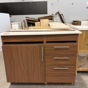 Brown cabinet with three drawers, one door, and a white countertop in a warehouse or workshop setting.