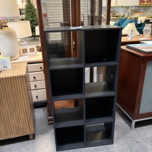 A black eight-cube storage shelf standing in a furniture store.