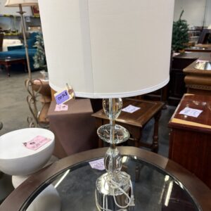 Table lamp with a drum shade, stacked glass base, and a price tag attached.