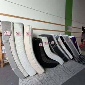 A row of various mattresses stood upright on a rug in a showroom.