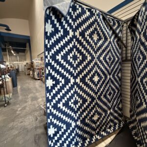 Navy blue and white rug with a geometric diamond pattern hanging in a store.