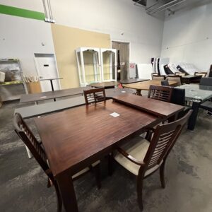 A dark wood dining table with slatted chairs in a furniture showroom.