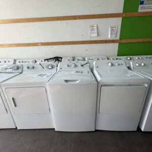 A row of white clothes dryers and washing machines for sale in a store.